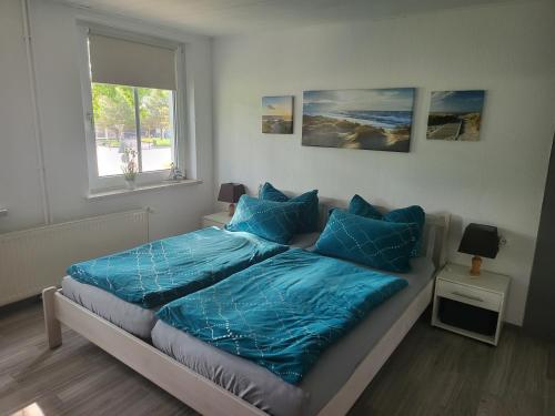 una camera da letto con un letto con lenzuola blu e una finestra di Ferienwohnung Altmann a Prerow