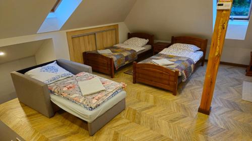 a attic room with three beds and a chair at Agroturystyka Pokój na Skarpie in Kowale Oleckie