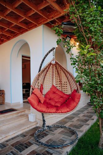 a hammock chair sitting on a patio at Tranquil Villa in Fayoum Private Pool Garden Lake Access in Kaḩk al Baḩrīyah