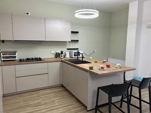 a kitchen with white cabinets and a counter with chairs at La dimora di Ipno in Vallata