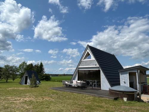 a small house with a gambrel roof on a field at A-Spot - A-formos nameliai ir poilsio sodyba in Roglaičiai I