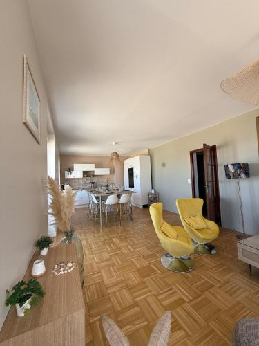 un salon avec des chaises jaunes et une table dans l'établissement La Plénitude face à la mer, à Dunkerque