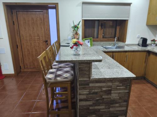 a kitchen with a counter with chairs and a sink at Casa do Tio Quim in Castelo de Paiva