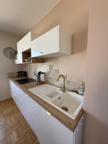 - une cuisine avec un évier et des placards blancs dans l'établissement La Plénitude face à la mer, à Dunkerque