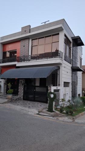 a white building with an awning on a street at Hill View Park Guest House Citihousing jhelum satellite town in Jhelum