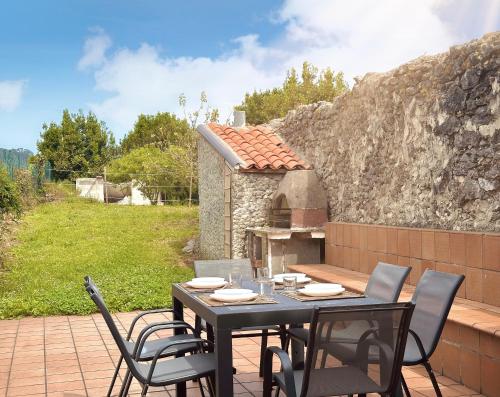 a table and chairs on a patio with a stone wall at A Babor - 20805 in Argoños