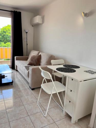 un salon avec une table et des chaises blanches dans l'établissement Chez Mika - Studio avec piscine, à La Celle-sous-Gouzon
