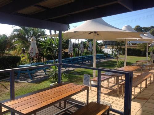 a group of benches with umbrellas and a pool at Tannum Sands Hotel / Motel in Tannum Sands