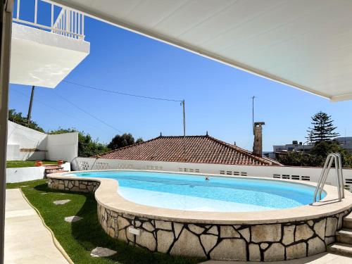 a large swimming pool in a yard with a patio at House T3 with Sea View and Private Pool - 5 minutes walk from the beach in Sesimbra