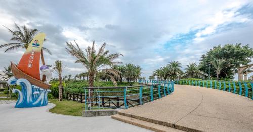 a curved walkway with a surfboard sign and palm trees at Duo Romance Hotel in Hualien City