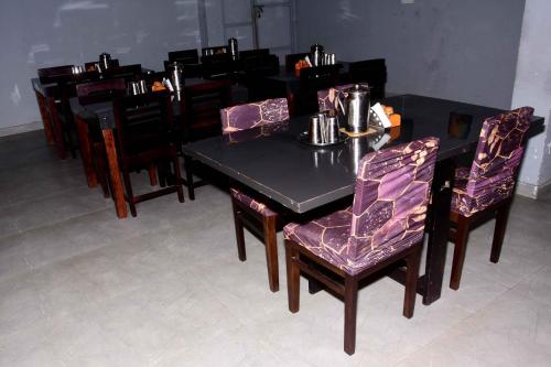 a black table with purple chairs and a dining room at Vanam Holidays in Ooty