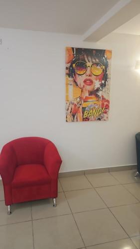 a red chair in a room with a painting on the wall at Apartahotel del Paseo in San José