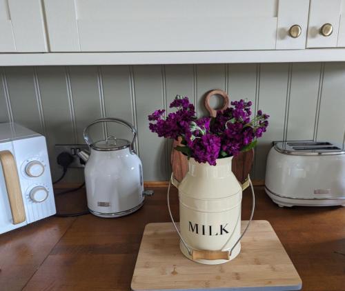 a vase filled with purple flowers sitting on a cutting board at Rose Valley Ballycastle in Ballycastle