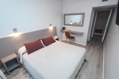 a bedroom with a white bed and a desk with a chair at Hotel Vip´s in Mar del Plata