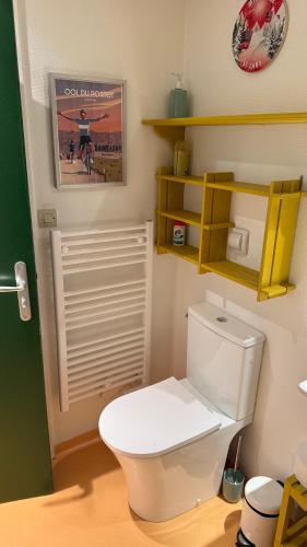 une salle de bain avec des toilettes blanches et des étagères jaunes dans l'établissement Studio Saint-Lary Soulan village, à Saint-Lary-Soulan