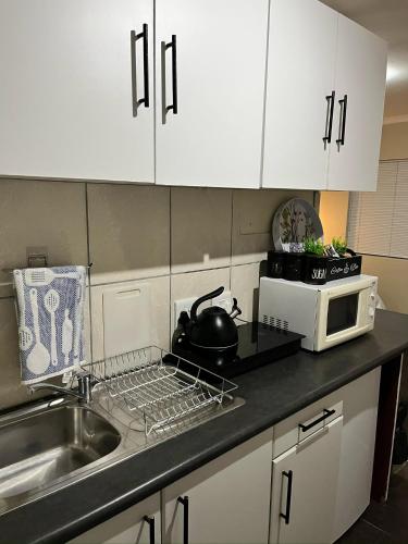 a kitchen with a sink and a tea pot on a drying rack at Brightways AirB&B in Summerstrand