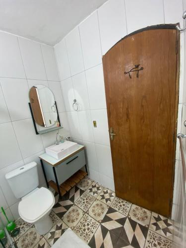 a bathroom with a toilet and a sink and a wooden door at Seu Cantinho de Paz em Iguape in Iguape