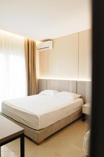 a bedroom with a white bed and a window at Hotel Mediterrane in Sarandë
