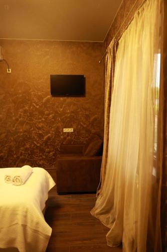 a bedroom with a bed and a television on a wall at GL Cottage in Tskaltubo