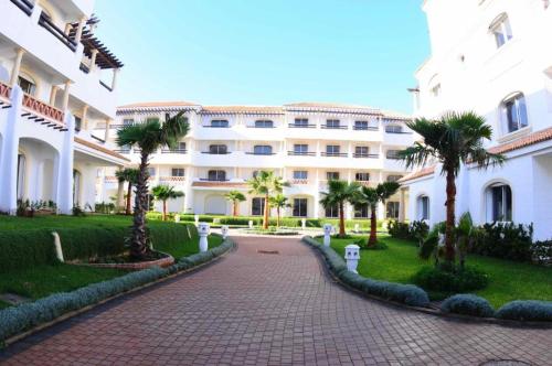 a large white building with palm trees in front of it at Duplex résidentiel Bord de mer in Casablanca
