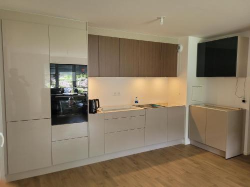 une cuisine vide avec des armoires blanches et une télévision dans l'établissement Chambre d'hôte, dans 4 pièce, avec terasse jardin, à Saint-Witz