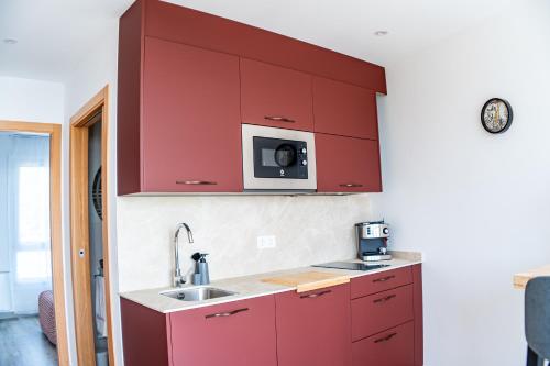 a red kitchen with a sink and a microwave at O da Sina-Los refugios del capitán BALLESTRINQUE in Aldán
