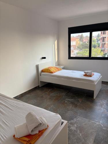 a white room with two beds and a window at Vila Enesa in Dobra Voda