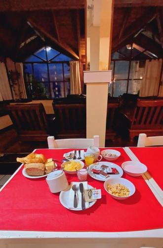 a red table with plates of food on a red table cloth at Hotel Costa del Lago in San Carlos de Bariloche