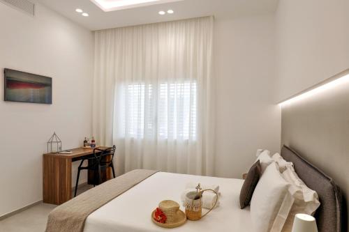 a white bedroom with a bed and a desk at Daline Holiday Rooms in Acquarica del Capo