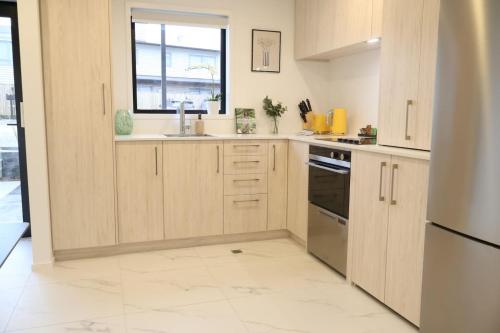 a kitchen with wooden cabinets and a window at Cosy 2BR House in Awaroa Road in Auckland