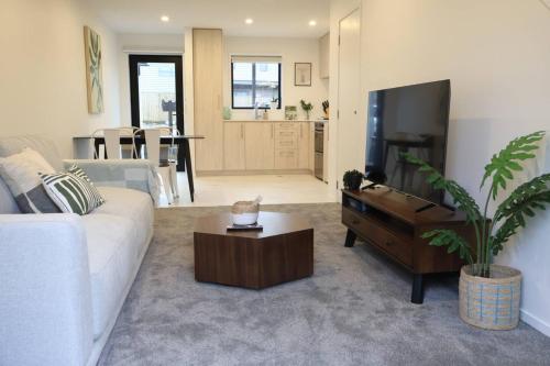 a living room with a white couch and a tv at Cosy 2BR House in Awaroa Road in Auckland