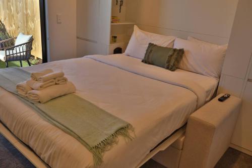 a large white bed with two towels on it at Cosy Studio in Awaroa Road in Auckland