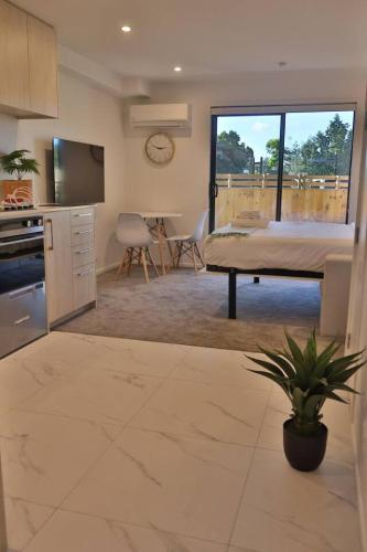 a kitchen and living room with a bed and a table at Cosy Studio in Awaroa Road in Auckland