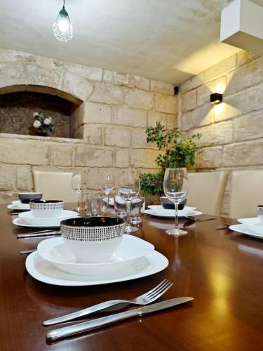 a wooden table with white plates and glasses on it at Casa Maltija in Sliema