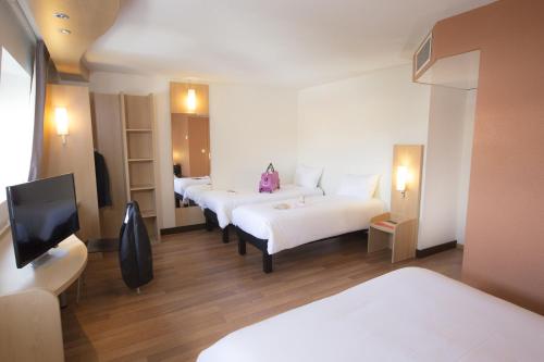 a hotel room with four beds and a flat screen tv at ibis Lille Lomme Centre in Lomme