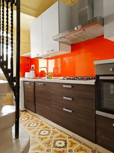a kitchen with orange walls and brown cabinets at Casa Maltija in Sliema