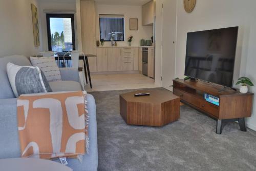a living room with a couch and a tv and a table at Cosy 2BR House in Awaroa Road in Auckland