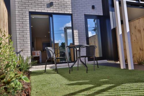 a table and chairs on a lawn in front of a house at Cosy 2BR House in Awaroa Road in Auckland