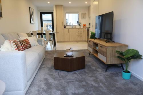 a living room with a white couch and a table at Cosy 2BR House in Awaroa Road in Auckland