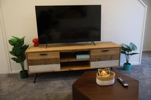 a flat screen tv sitting on top of a wooden entertainment center at Cosy 2BR House in Awaroa Road in Auckland