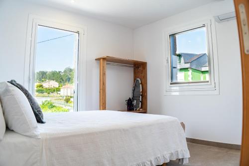 a white bedroom with a bed and a window at O da Sina- Los refugios del capitán AS DE GUÍA in Aldán