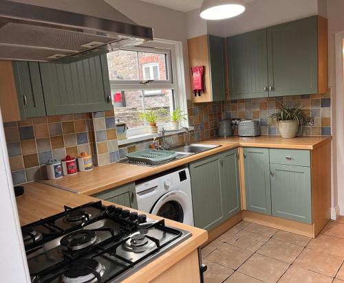 a kitchen with green cabinets and a stove top oven at Kookaburra Cottage in Brecon
