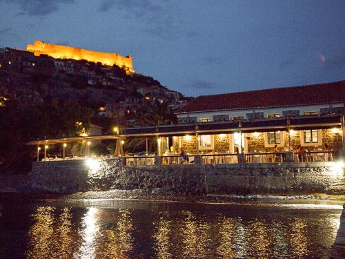 a restaurant on the water at night with the castle at Olive Press Hotel in Mithymna