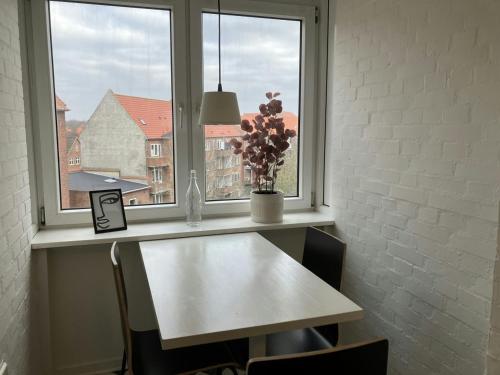 une table devant une fenêtre avec un vase de fleurs dans l'établissement Convenient Studio for 2, à Esbjerg