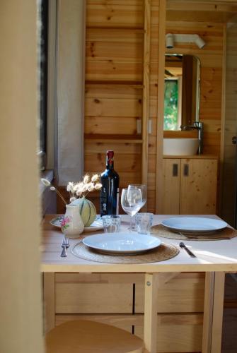 - une table avec deux assiettes et des verres à vin dans l'établissement Le Petit Lodge du Cotentin - Tiny House cosy à 800 m de la mer, à Flamanville