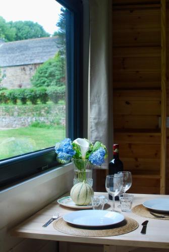 une table avec un vase de fleurs et une fenêtre dans l'établissement Le Petit Lodge du Cotentin - Tiny House cosy à 800 m de la mer, à Flamanville