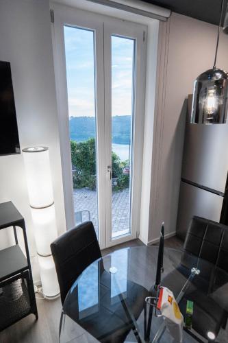 a dining room with a glass table and a large window at Klimt & Van Gogh Vista Lago by Abitare Il Tempo in Nemi