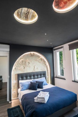 a bedroom with a large bed with blue sheets and two lights at Klimt & Van Gogh Vista Lago by Abitare Il Tempo in Nemi
