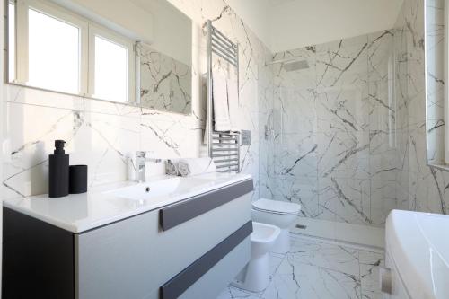 a white bathroom with a sink and a toilet at Free Parking Elmi - due passi dal Lago Maggiore in Arona