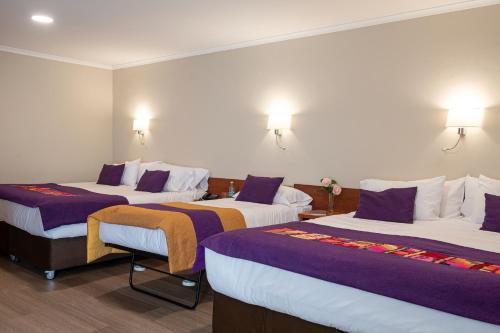 a hotel room with two beds with purple sheets at Hotel Madero Talca in Talca